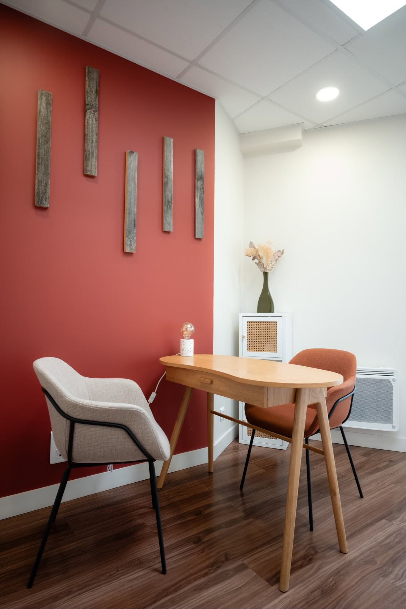 Cabinet de consultation avec mur terracotta, mobilier en bois clair et fauteuils chaleureux